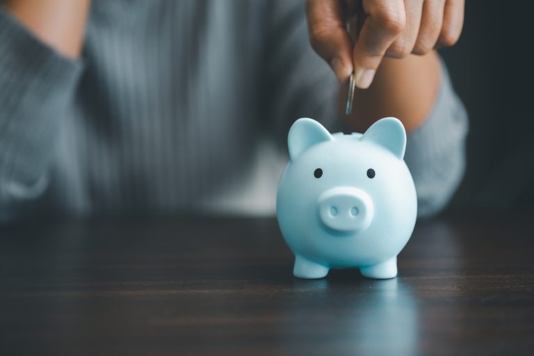 Coin is held over open slot in piggy bank
