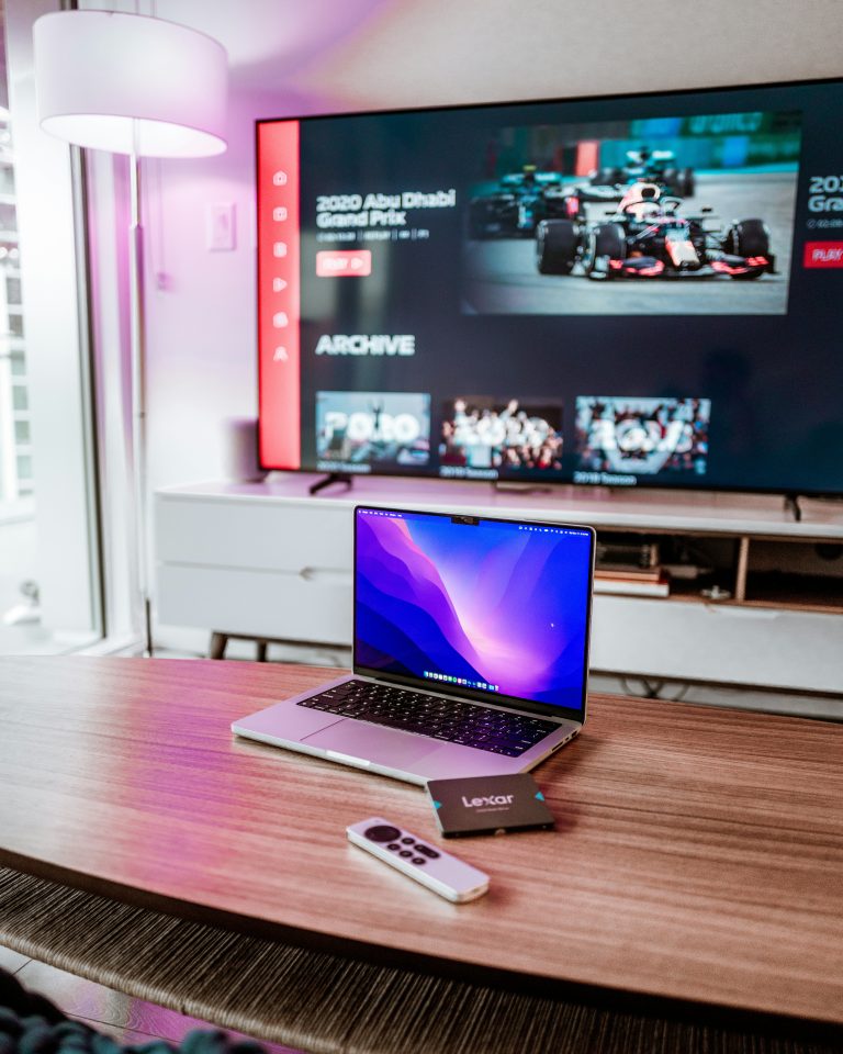 A computer sitting on a coffee table in front of a TV.