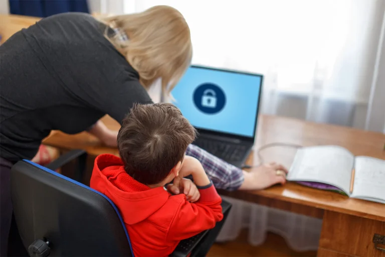 Parent and child working on a laptop with security screen displayed.