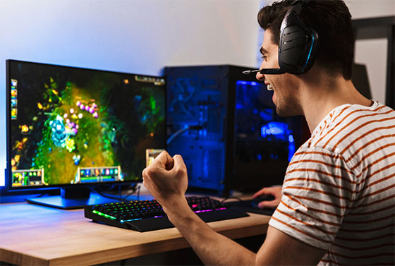 Excited man playing a computer game wearing a headset.