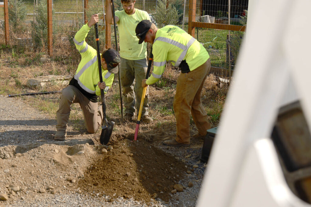 Workers digging underground fiber cable for installation.
