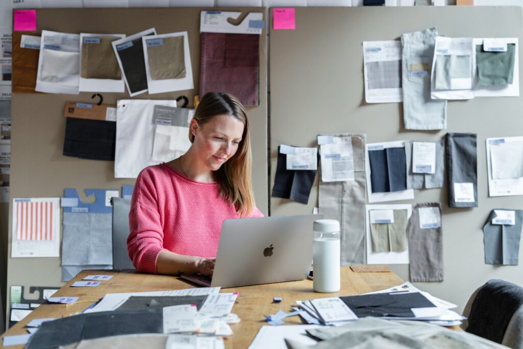 Small business owner on her laptop with fabric swatches on the wall.
