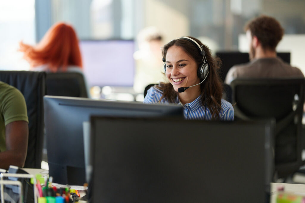 Happy businesswoman working on desktop PC as an IT support for customers in the office.