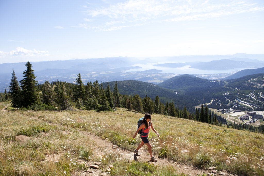 A woman hiking up Mt. Schweitzer while overlooking Sandpoint Idaho and Lake Pend Orielle.