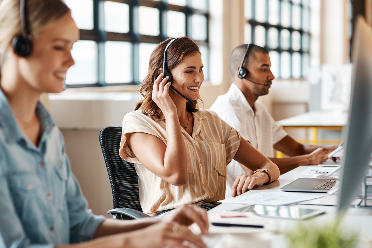 intermax-networks-cloud-communications-101-2 Women and a man with headsets on in an open plan office.