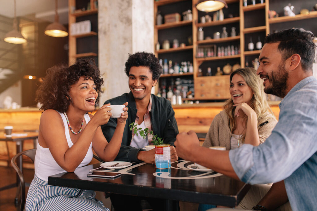 Four friends sitting in a coffee shop and smiling.