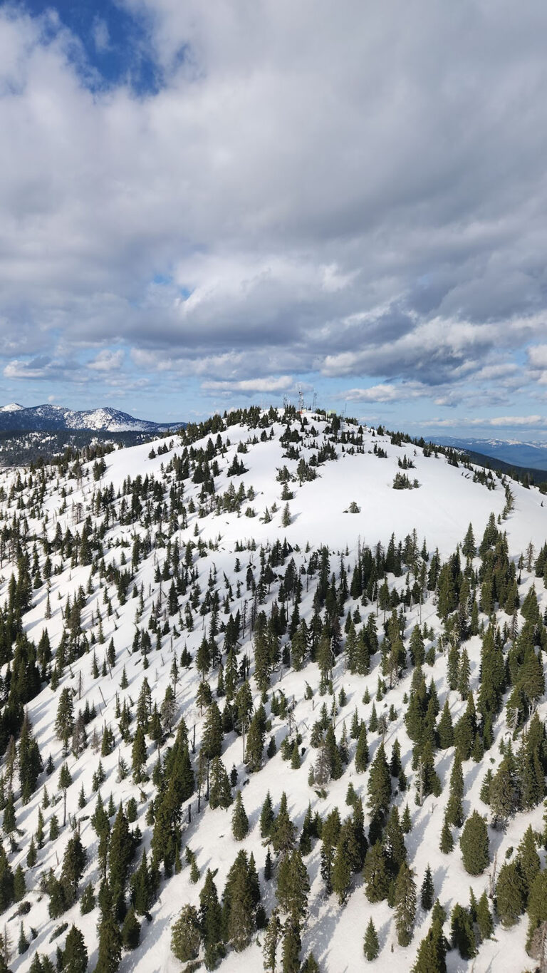 Baldy mountain summit covered in snow with tower on top.
