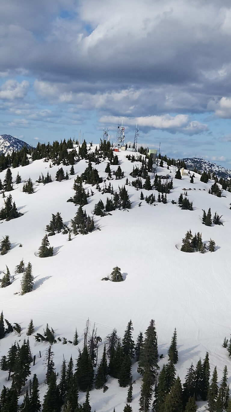Baldy mountain summit covered in snow with tower on top.