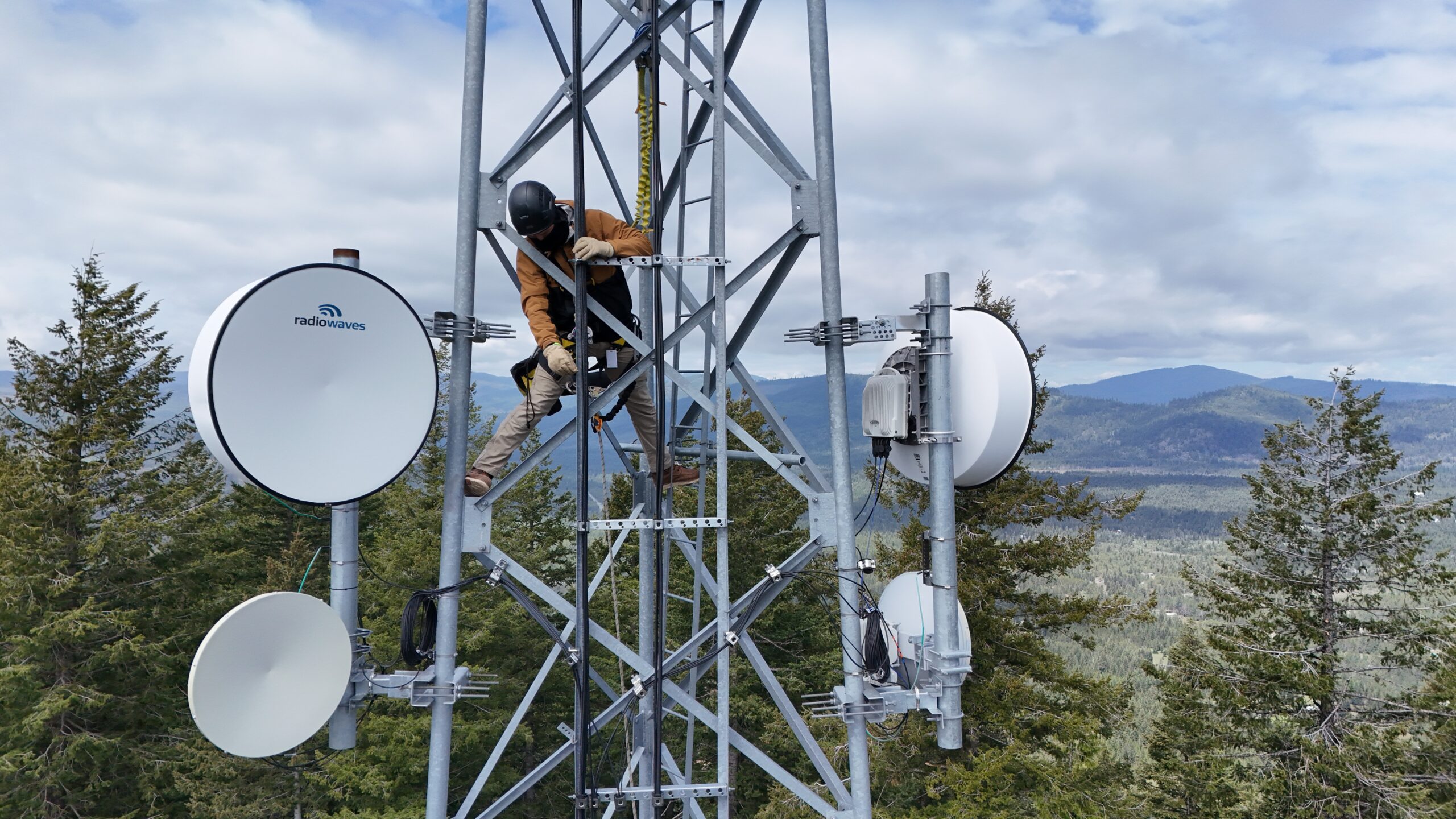 Intermax fixed wireless tech in a tower surrounded my treetops and mountains in the distance.