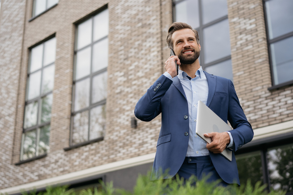 Businessman talking on mobile phone and holding laptop.
