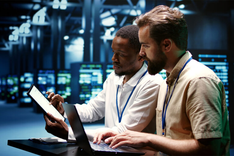 Team collaborating around a computer in a modern office, discussing IT solutions and business strategy.