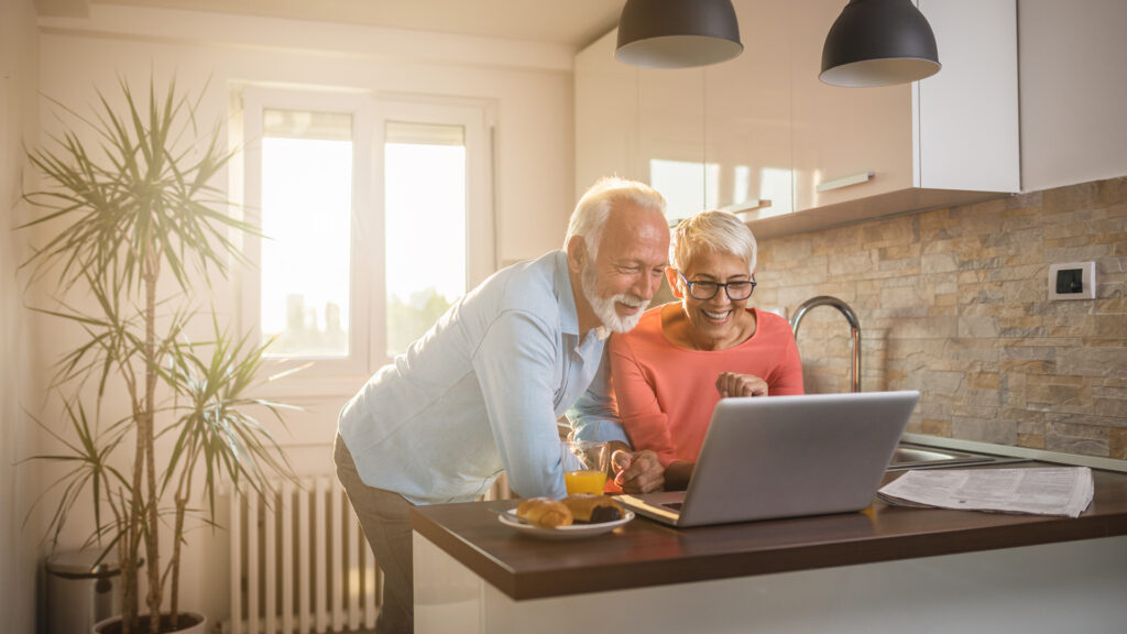 Senior couple staying in touch with their family using their laptop at home