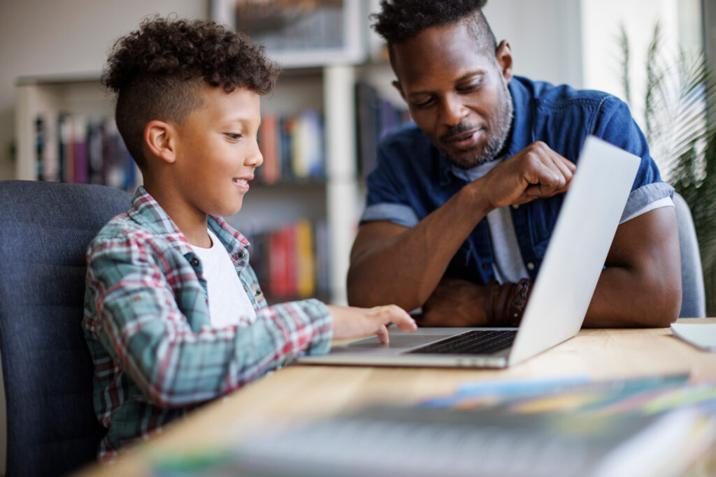 Father and son using laptop at home