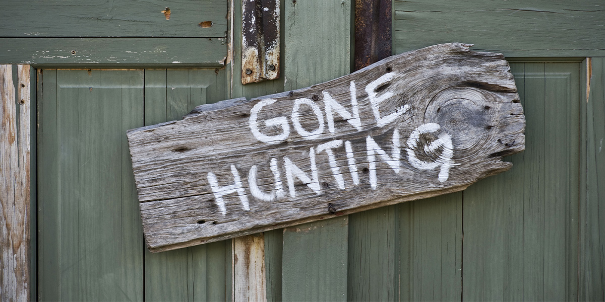 Wood "Gone Hunting" sign on a green door.