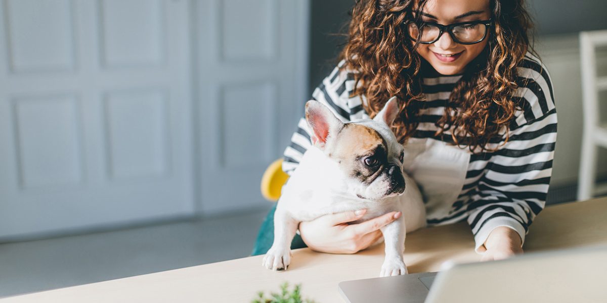Woman with dog working in a home office.