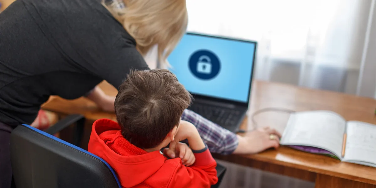 Parent and child working on a laptop with security screen displayed.