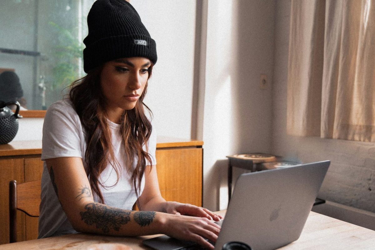 dushawn-jovic-4JpCi9jWaOA-unsplash Female photographer looks at laptop while typing looking concentrated, camera lying on table