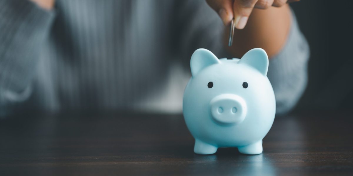 Coin is held over open slot in piggy bank