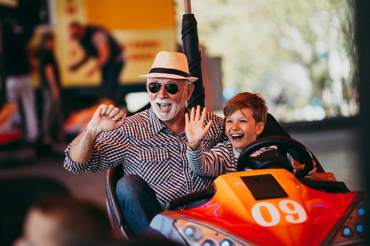 Grandfather and grandson driving bumper car together.