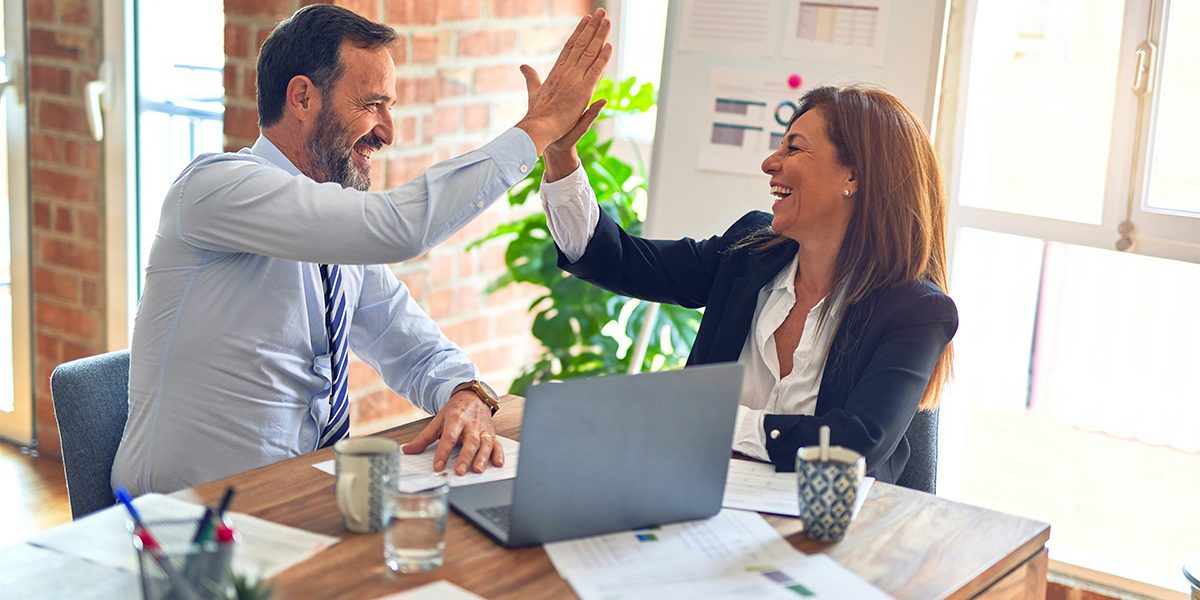 Two middle age business workers smiling happy and confident, high-fiving