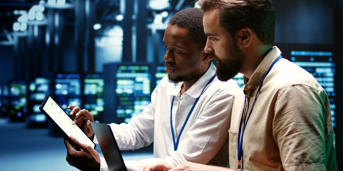 Team collaborating around a computer in a modern office, discussing IT solutions and business strategy.