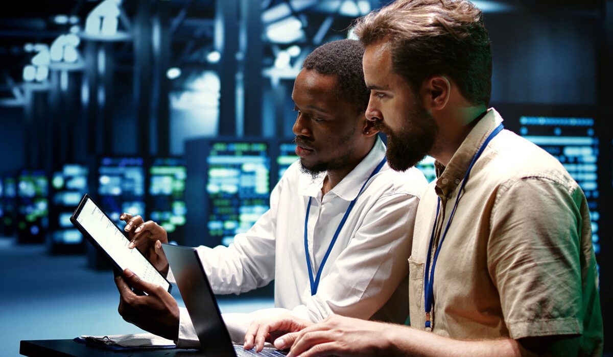 Team collaborating around a computer in a modern office, discussing IT solutions and business strategy.