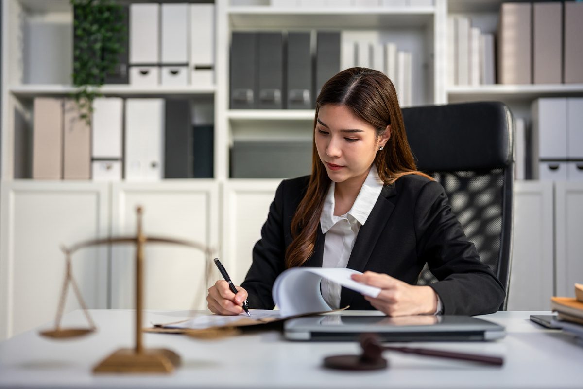Female attorney looks at a document while sitting at her desk.