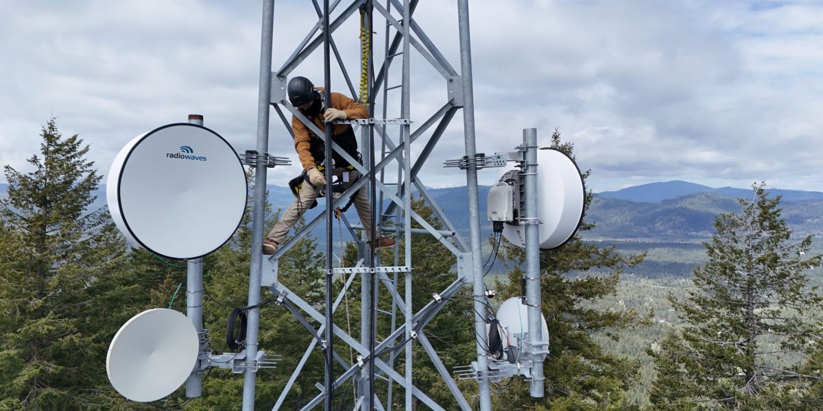 Intermax fixed wireless tech in a tower surrounded my treetops and mountains in the distance.