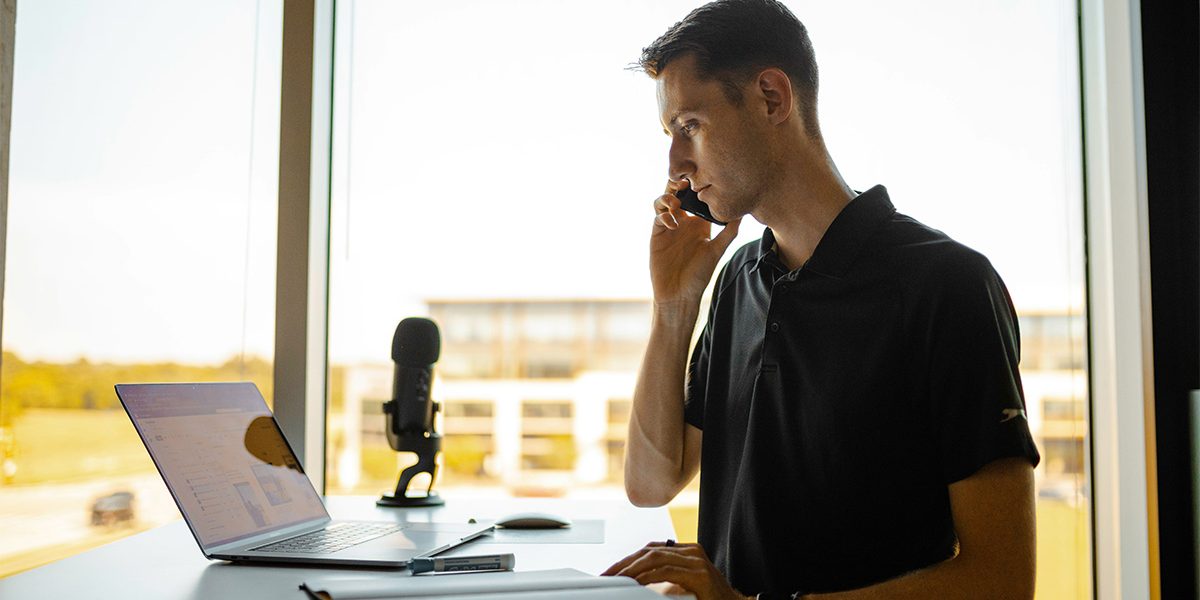 Male on the phone working on the computer at his desk with a view from his office. Photo by Chase Chappell on Unsplash